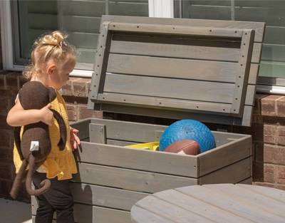 Little Girl Putting Toys in Jack and June Wooden Toy Chest